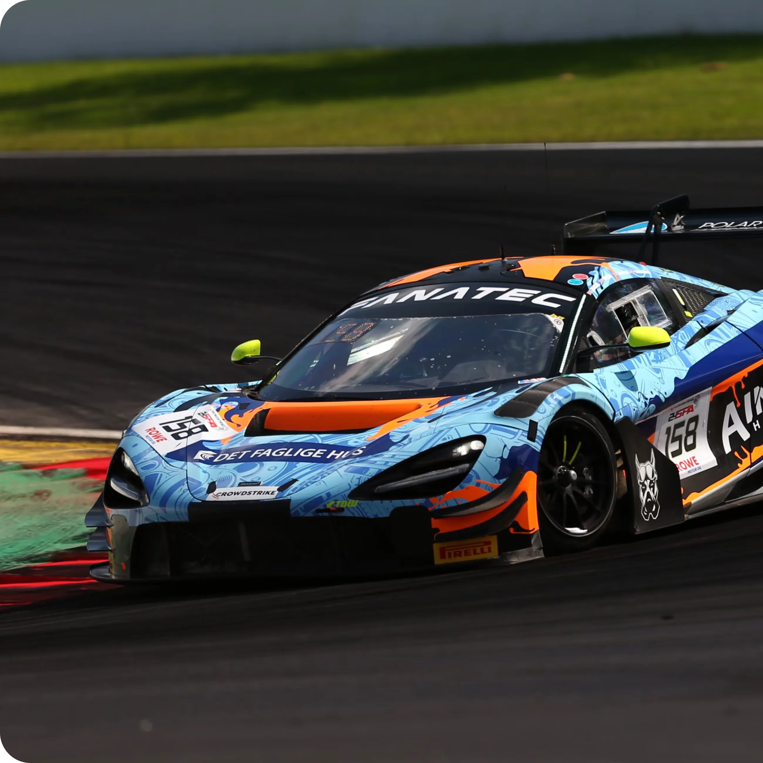 A blue-and-orange McLaren GT3 race car with Fanatec livery cornering on a dark track